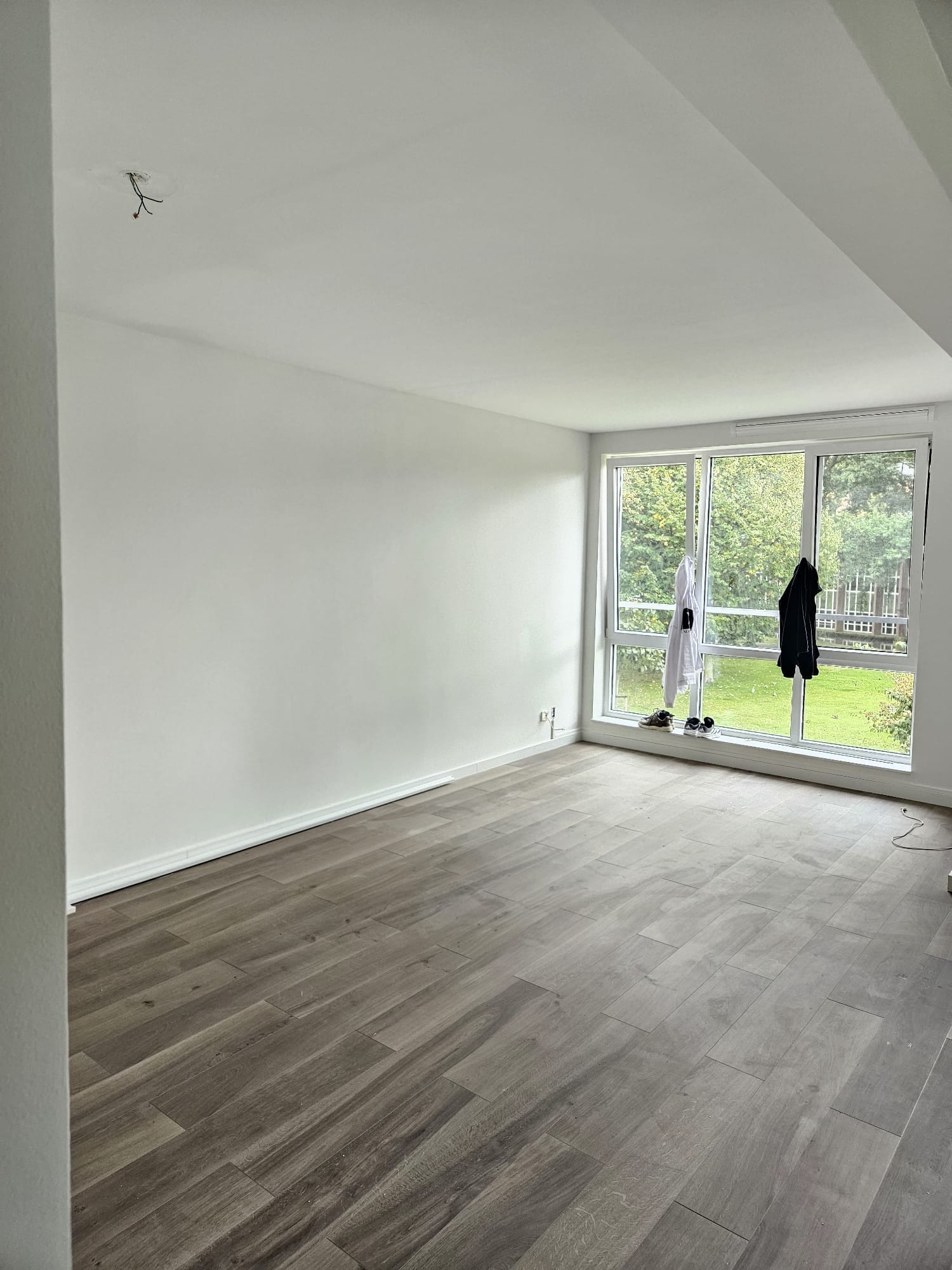 Lege woonkamer met strak afgewerkt stucwerk op wanden en plafond en een groot hoekraam